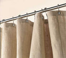Beige curtains hanging on a rod against a beige wall