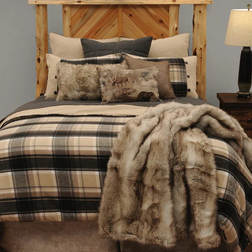 Bed with plaid bedding and fur throw, wooden headboard, and lamp on nightstand - Blue Mountain Brands USA