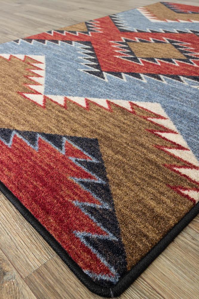 southwestern area rug with red, blue, and brown geometric diamond pattern on wood floor, western style performance rug