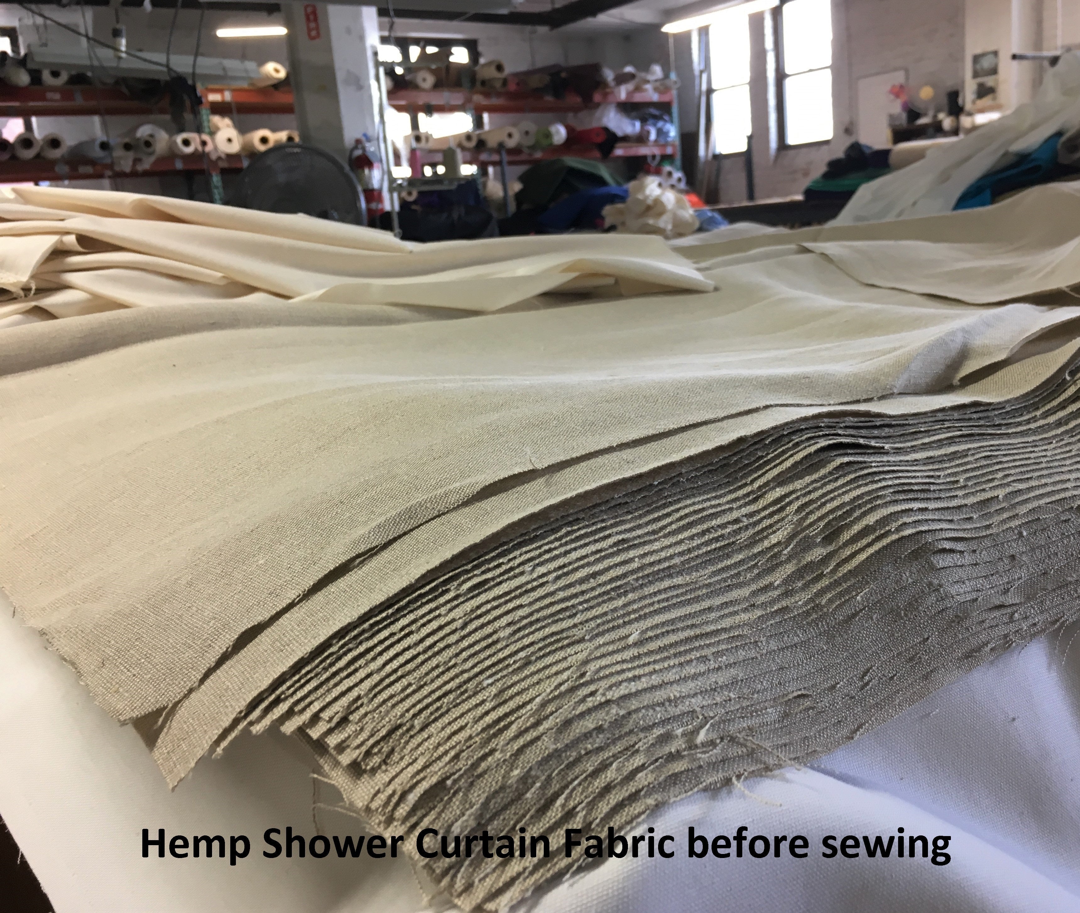 Stack of hemp shower curtain fabric before sewing in a warehouse setting