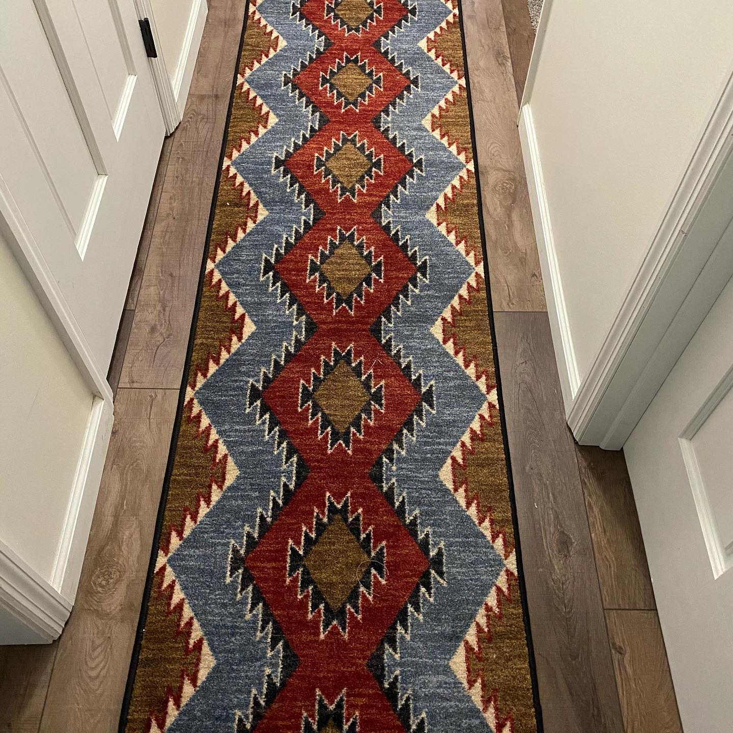 southwestern floor runner with red, grey/blue, and brown geometric diamond pattern on wood floor, western style performance rug