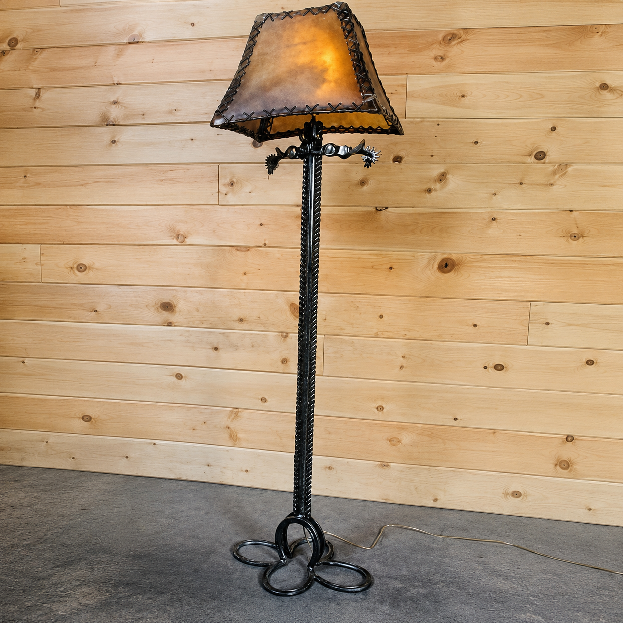 Handmade iron spur floor lamp with horseshoes, braided iron and spurs. Shown with a custom made rawhide lamp shade