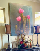Decorative table with a large cactus painting, lamps, and a floral arrangement - American made art by artist Sherri Alexander for Blue Mountain Brands USA