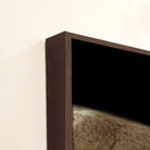 Close-up of a dark wooden frame with a blurred image of a planet or moon on a light beige background